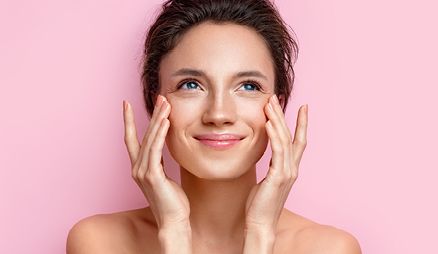 Women touching her cheek bones with pink background