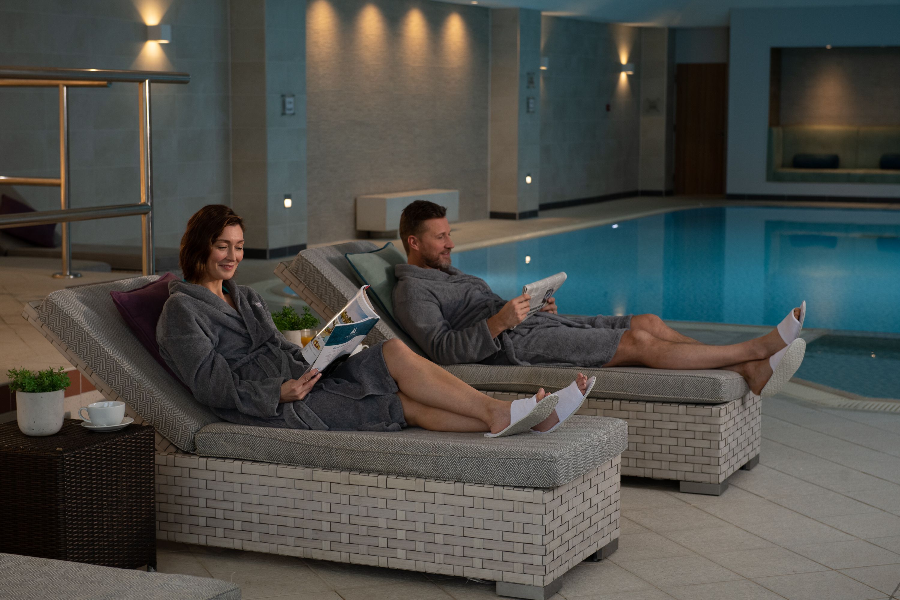 Couple relaxing on spa loungers by pool