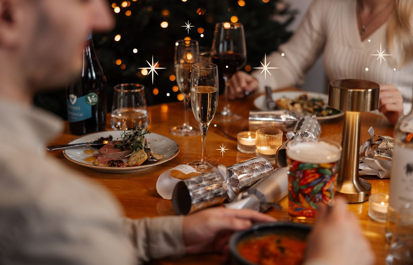 Christmas dining with food, drinks and crackers on table with sparkles