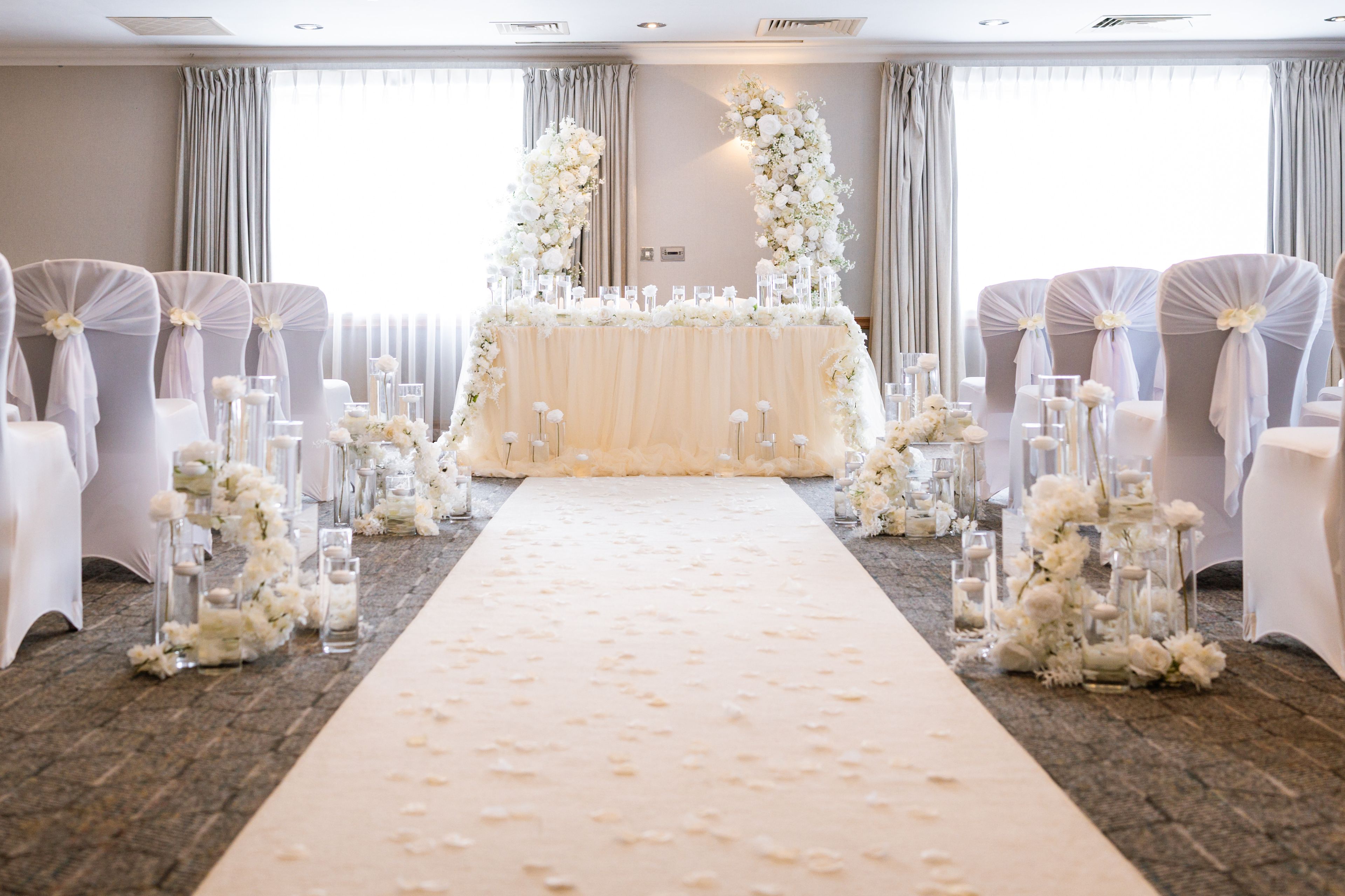 Room dressed for wedding ceremony with white flowers and chairs